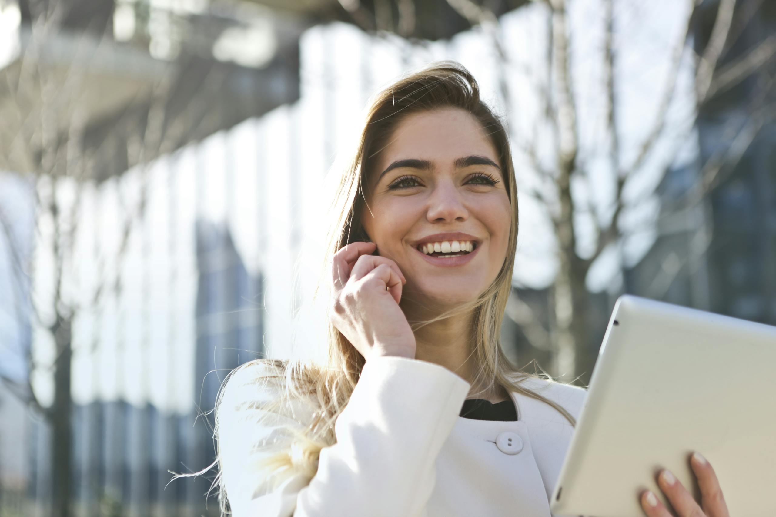 Uśmiechnięta kobieta biznesu z tabletem i telefonem – nowoczesna edukacja BHP online