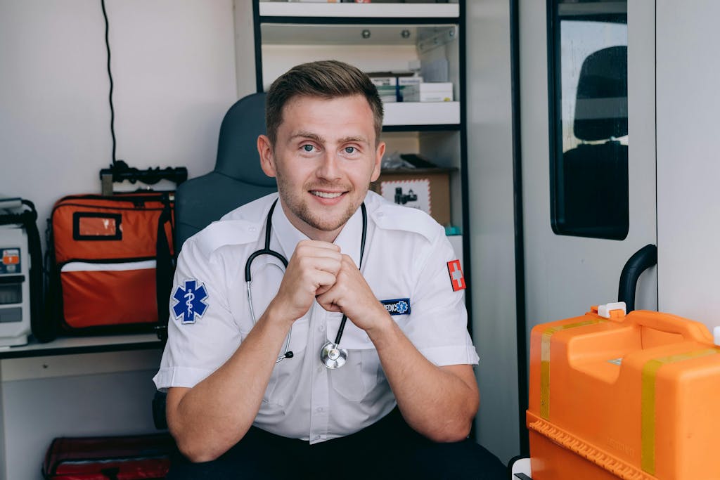 Ratownik medyczny w mundurze siedzący w ambulansie – symbol nowej definicji pierwszej pomocy w BHP