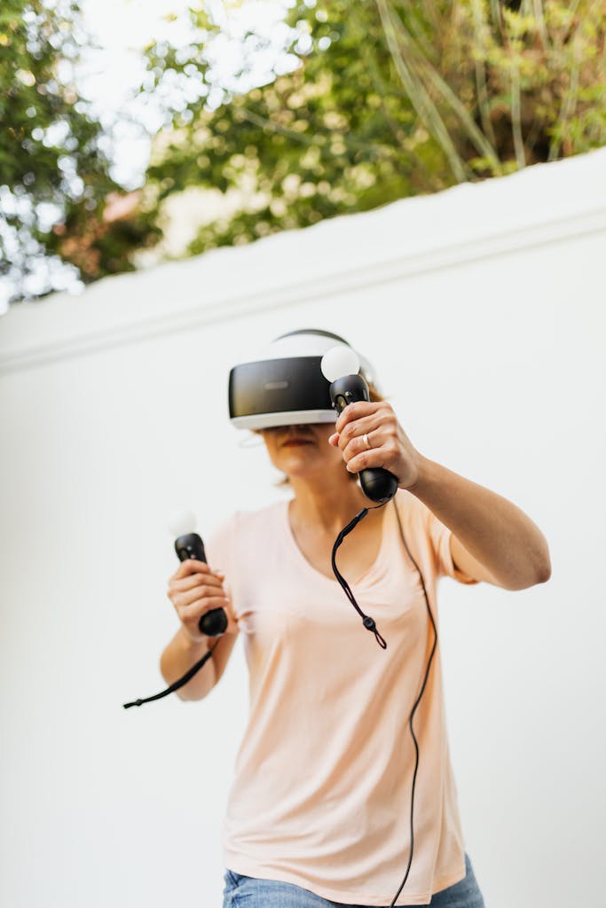 Adult woman enjoying virtual reality gaming with VR headset outdoors on a sunny day.
